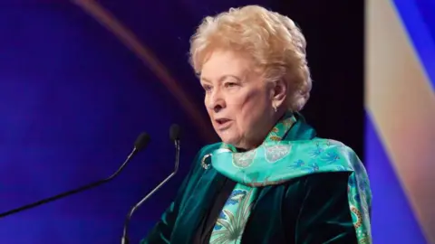 Getty Images Baroness O'Loan in green suit and scarf giving a speech at microphone